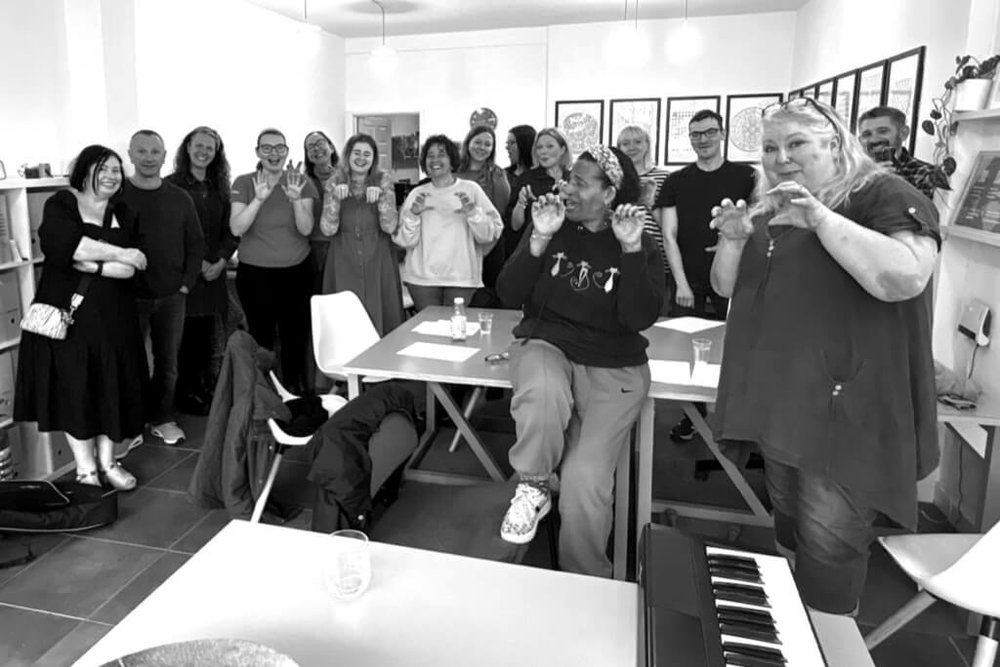 A group of people singing and making funny hand gestures, rendered in black-and-white